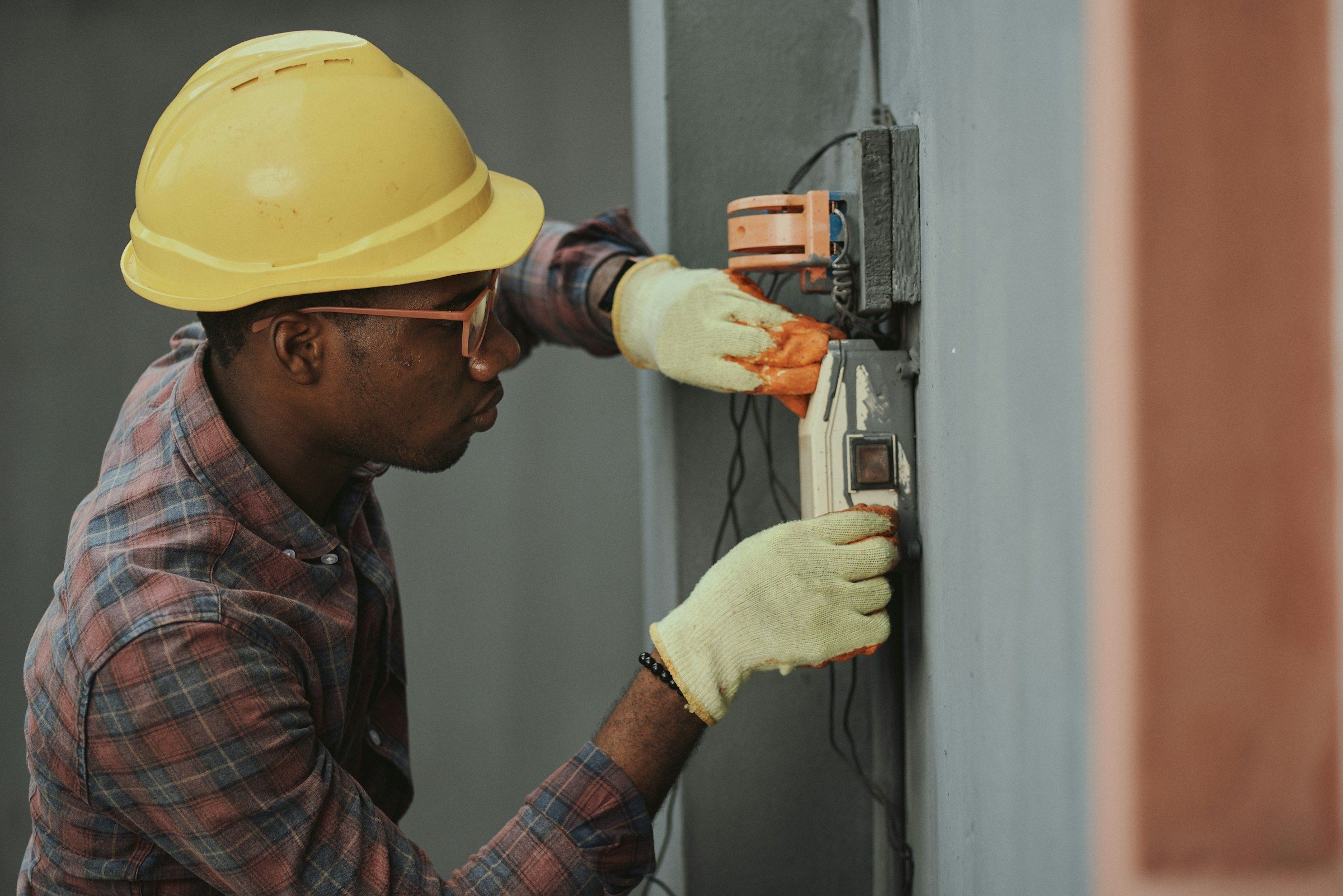 Eletricista com capacete instalando fiação em um quadro